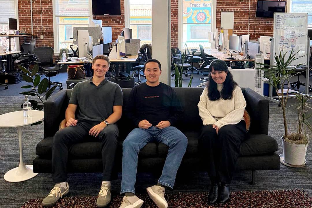 Kevin Wu, the CEO of Leaping AI sits on a black couch with two employees who are forward deployed engineers.